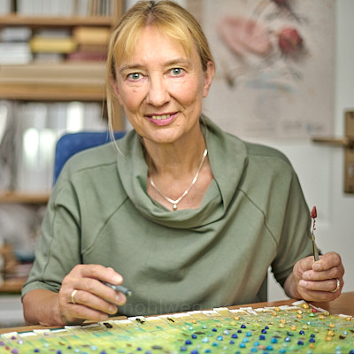 Porträt der Künstlerin Magdalena Hohlweg in ihrem Atelier bei der Arbeit an Miniaturcollagen.